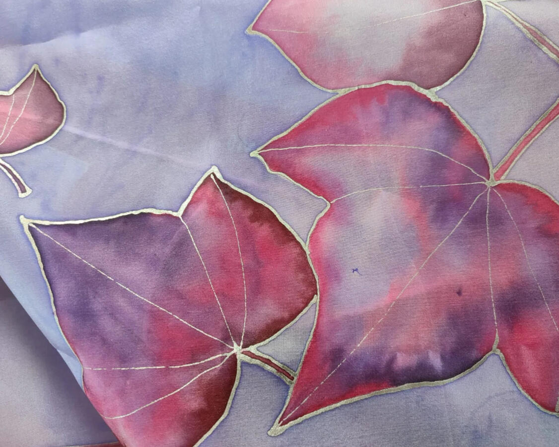 Pañuelo de seda natural pintado a mano a pincel con guta blanca con motivos de hojas de hiedra en tonos morados y rosas sobre fondo lila.